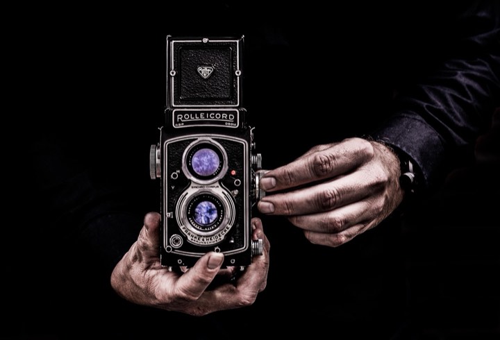 Hands holding a vintage twin-lens camera