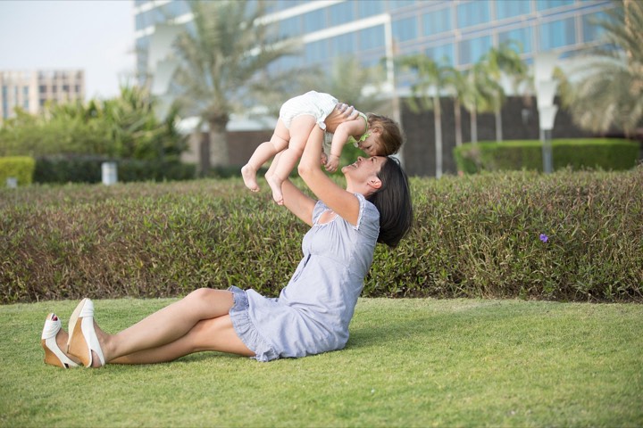 A dad lifting his baby up on the grass