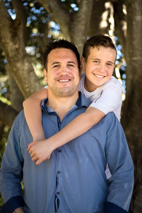 A boy hugging his dad from behind