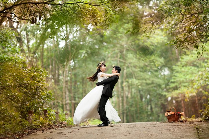 A groom spinning his bride in a pine forest
