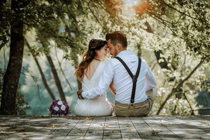 A bride and groom sitting close under blossoming trees