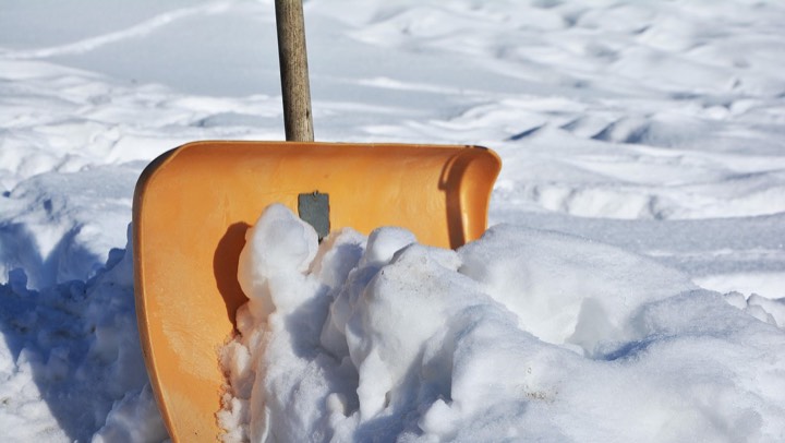An orange snow shovel in fresh snow